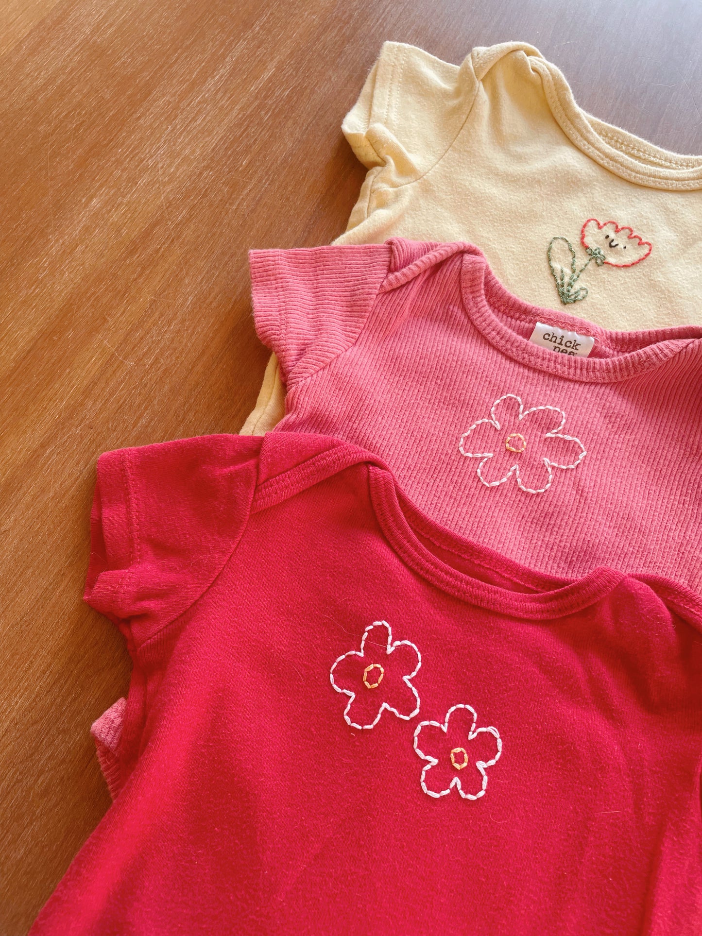 Flowers Hand embroidered on thrifted onesies